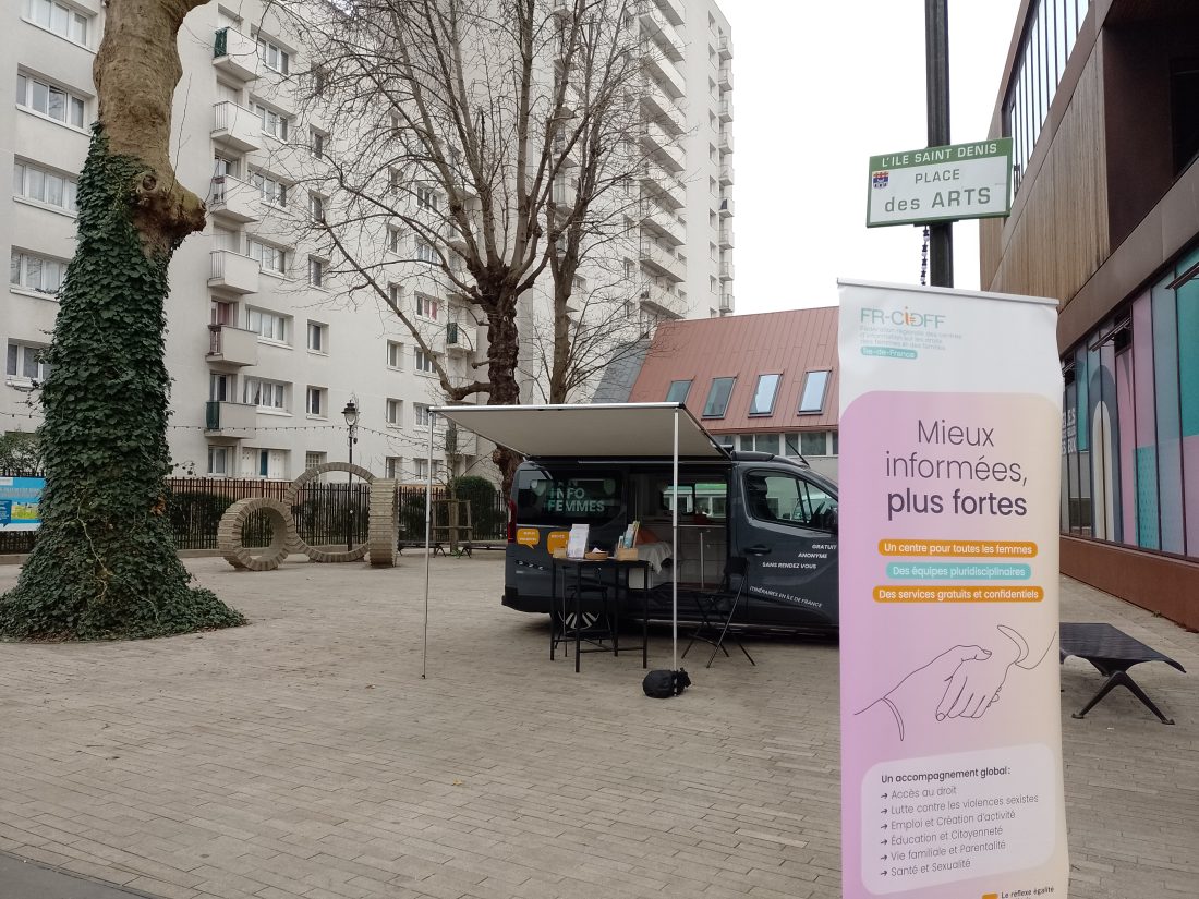 Le Van Info Femmes installé sur une place, avec un kakémono 
